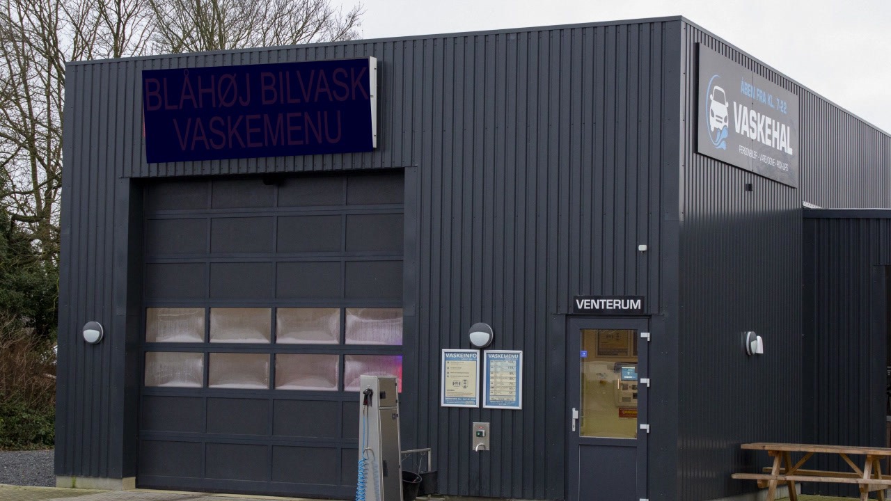 Mørk vaskehal med et LED-skilt over porten hos Blåhøj Bilvask