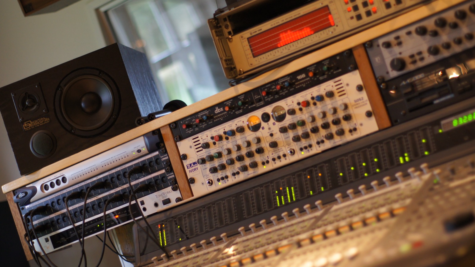 Mixerpult og rack med udstyr i lydstudiet. Lysdioderne på pulten lyser grønt